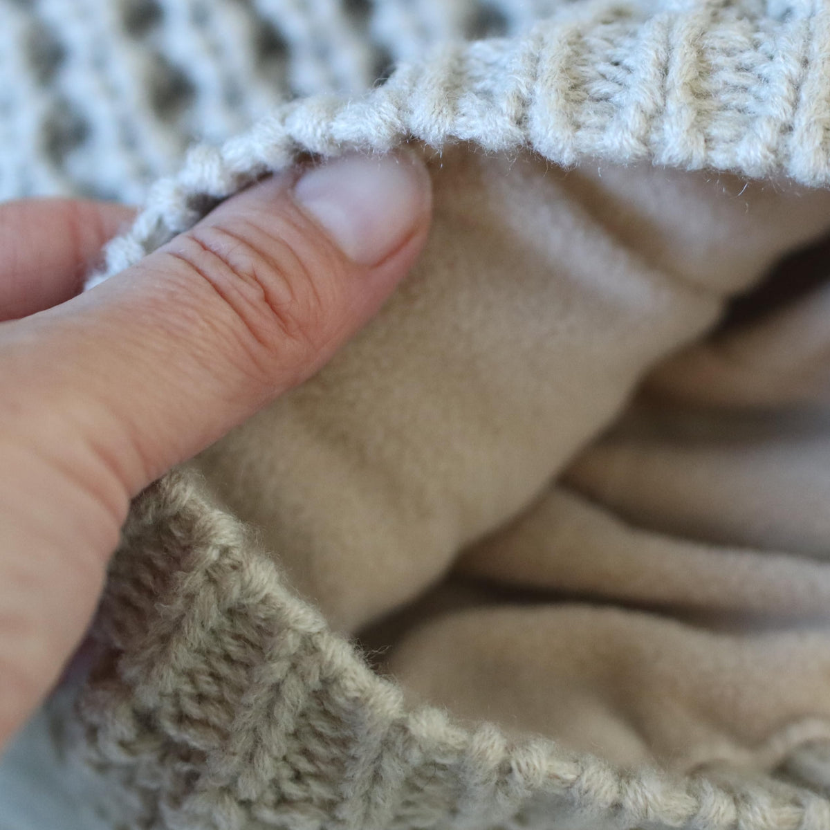 Beige knit beanie opened to show its soft fleece lining