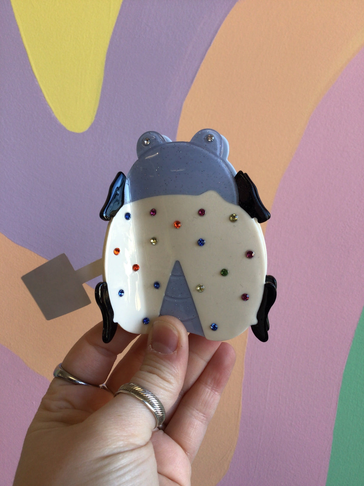 Blue ladybug-style hair claw with white body and multicolor dot accents