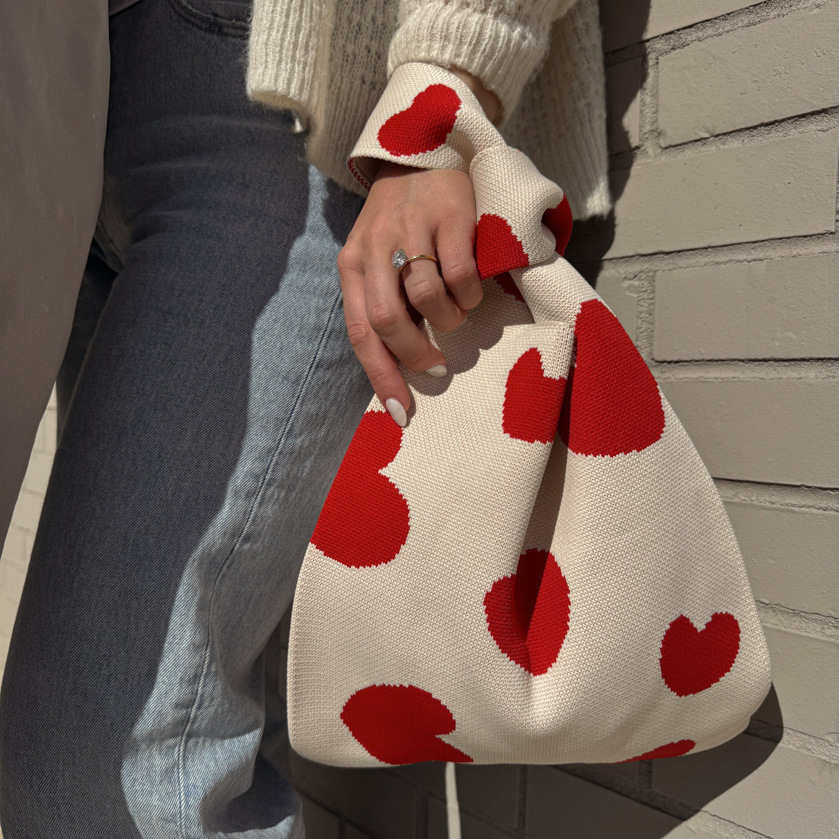 Cream heart-print drawstring handbag with gathered top, held upright