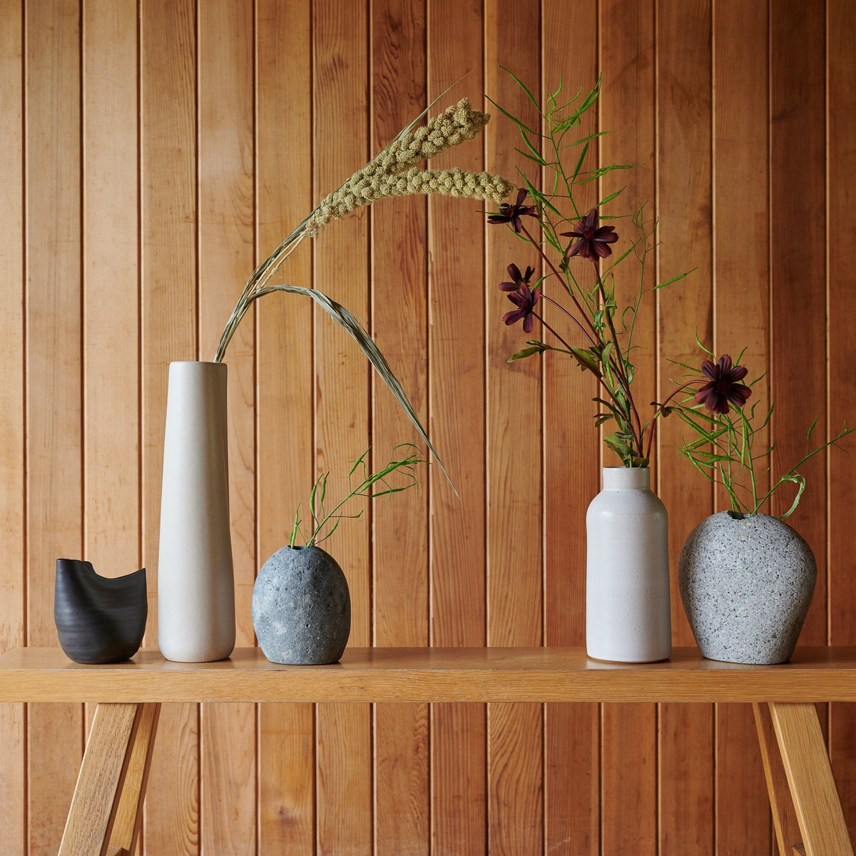 Black bird-shaped vase in wood-shelf arrangement, holds floral stems