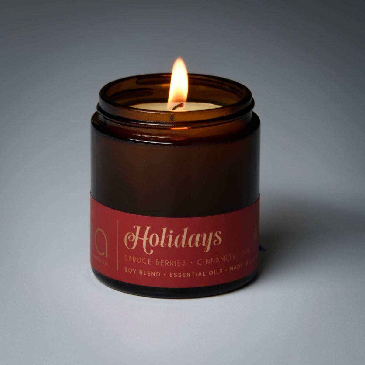 Lit amber glass soy candle jar with label and one flame