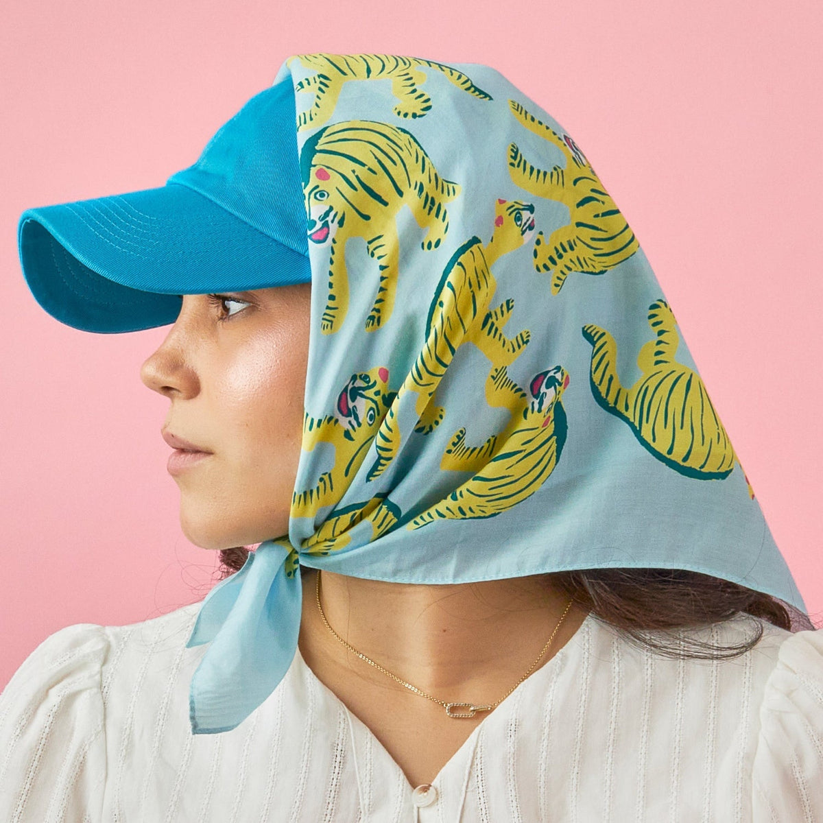 Blue tiger-print bandana worn as head scarf with pointed knot.