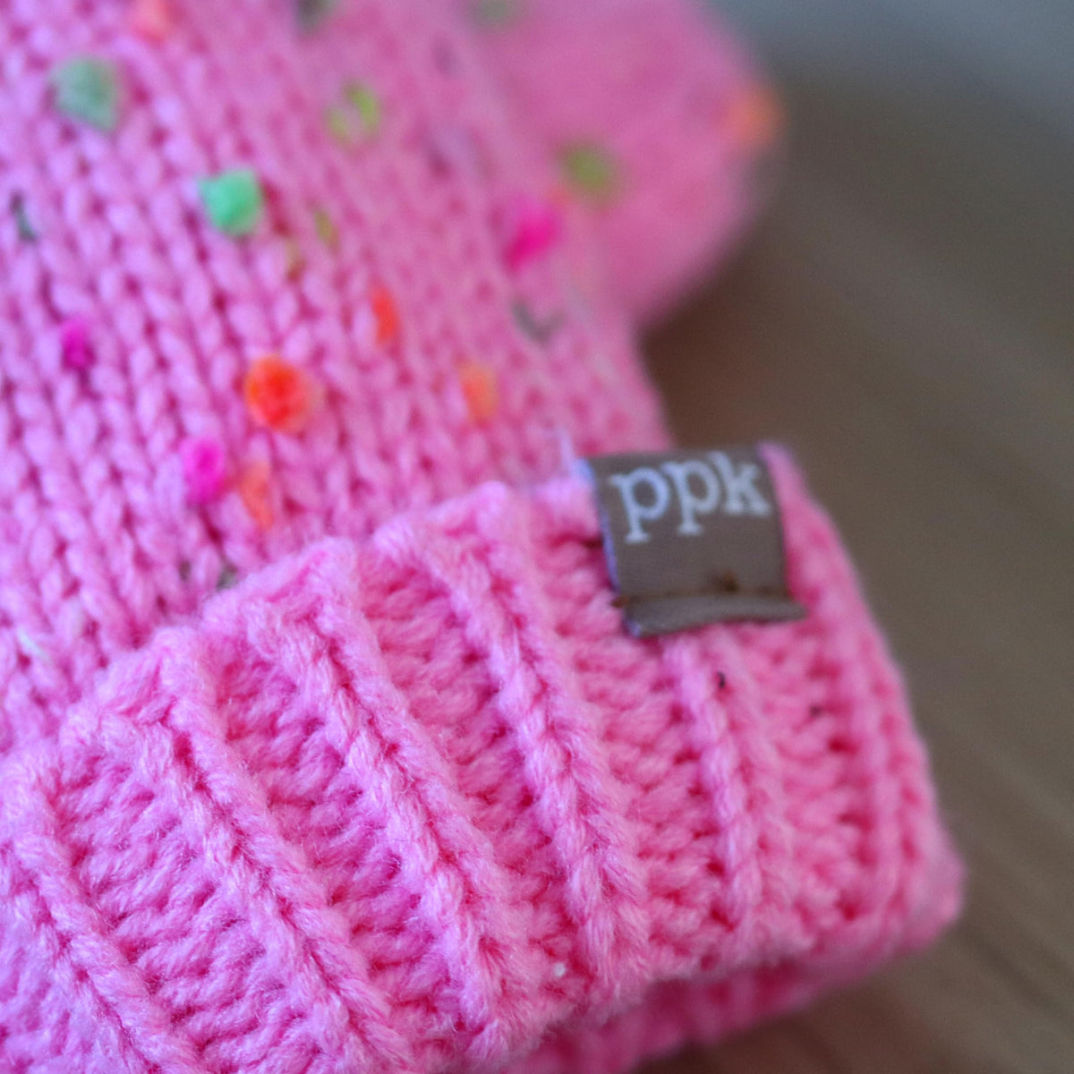 Close-up of pink speckled knit mitten cuff and fabric label