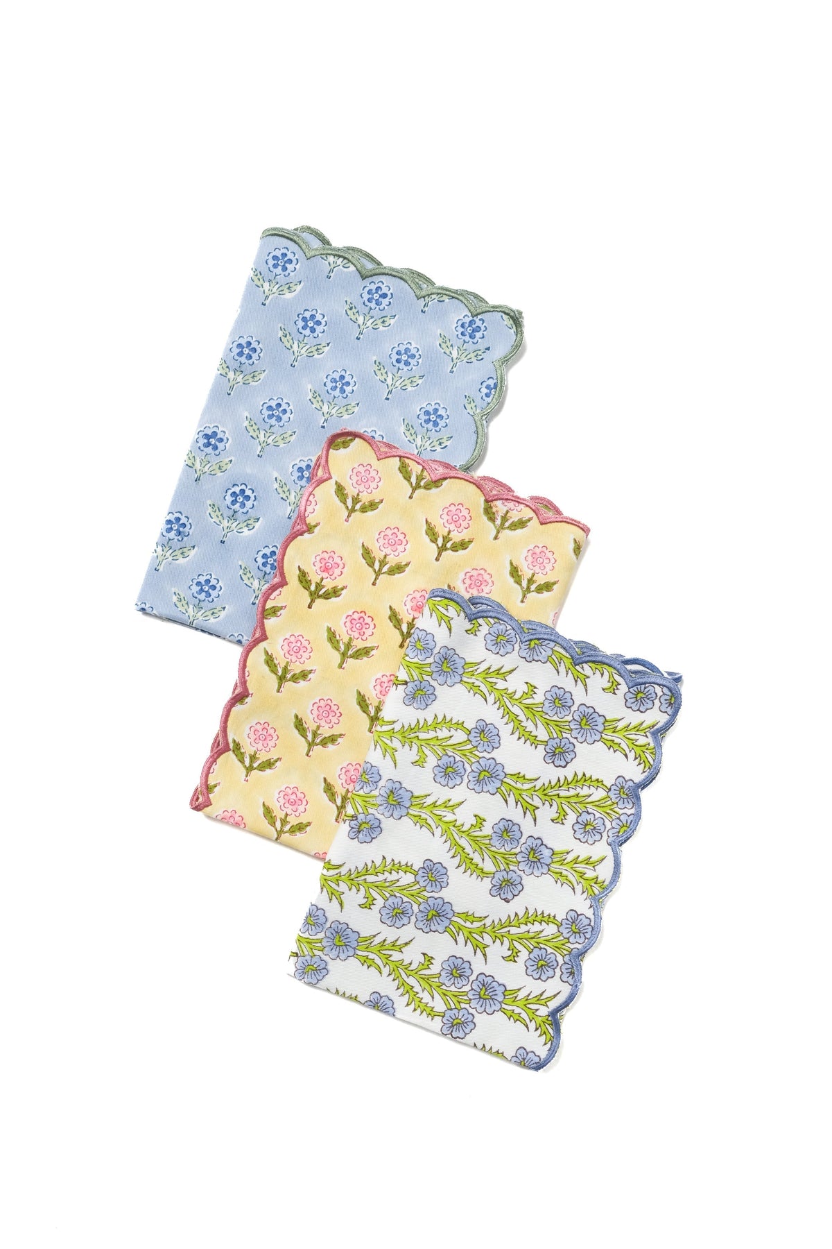 Stacked scallop-edge napkins in blue with embroidered florals in yellow, pink, and green