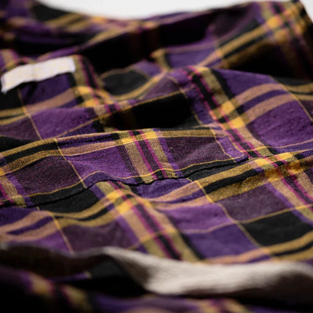 Close-up of purple plaid apron fabric with yellow and black woven stripes
