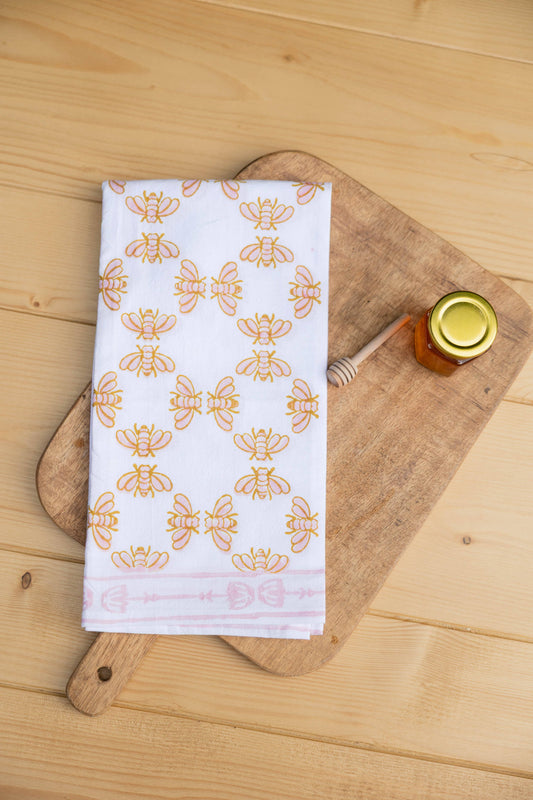 Tea towel, white with orange honeybee pattern, folded with stitched edge