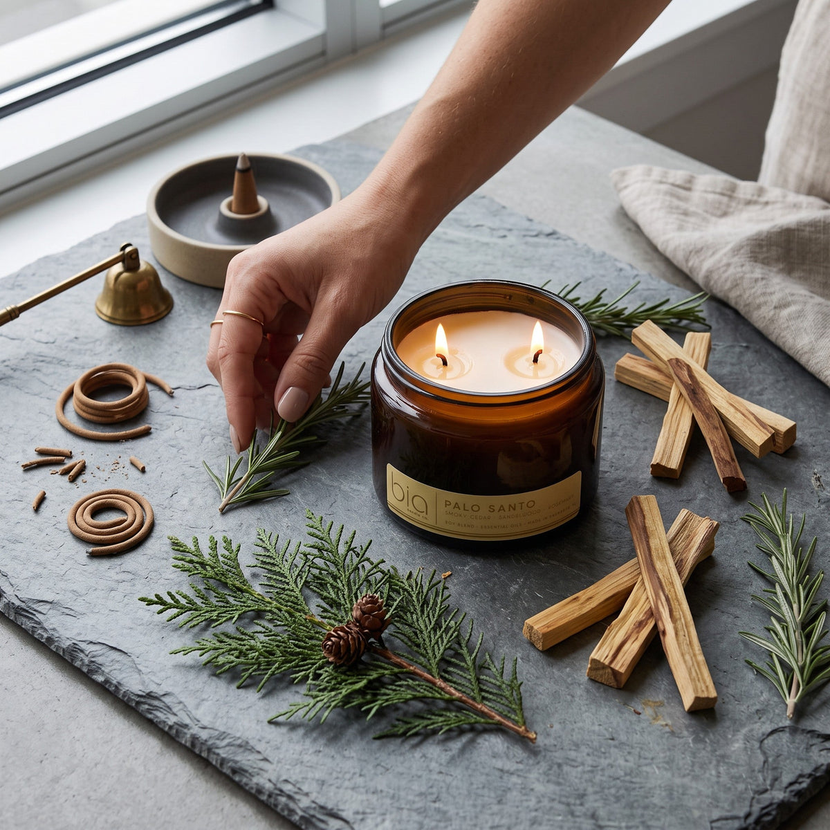 Amber soy candle jar with two lit flames and palo wood pieces