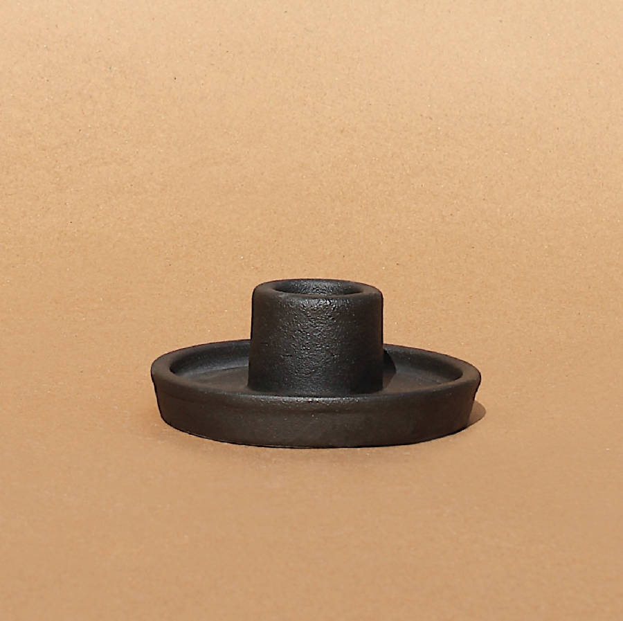 Black ceramic candle holder on a flat base with raised center cup