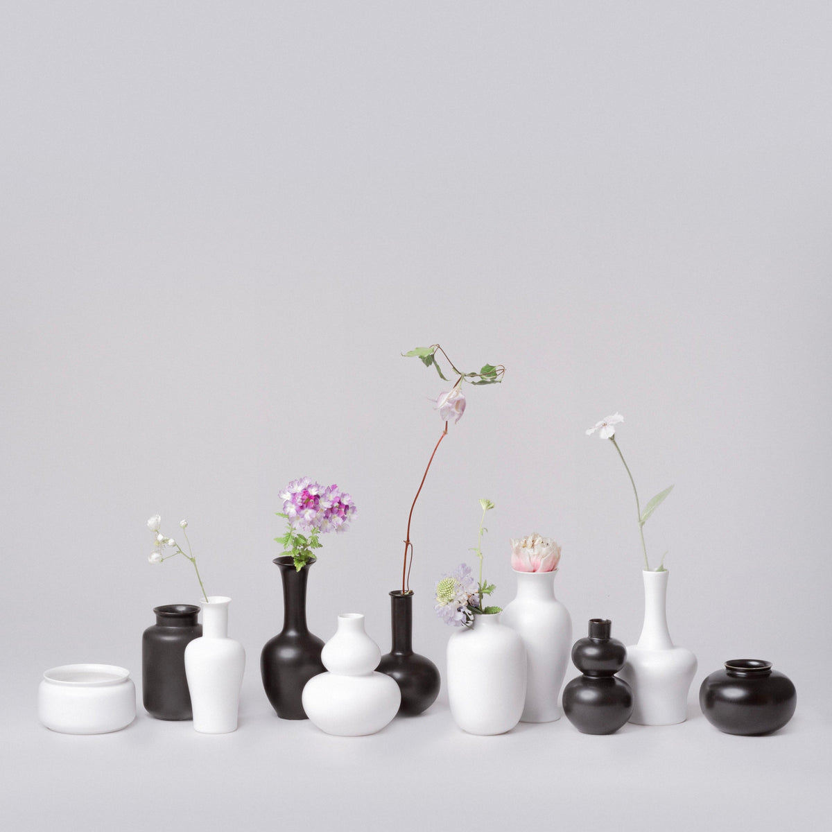 Assorted small vases in white and dark finishes with flowers