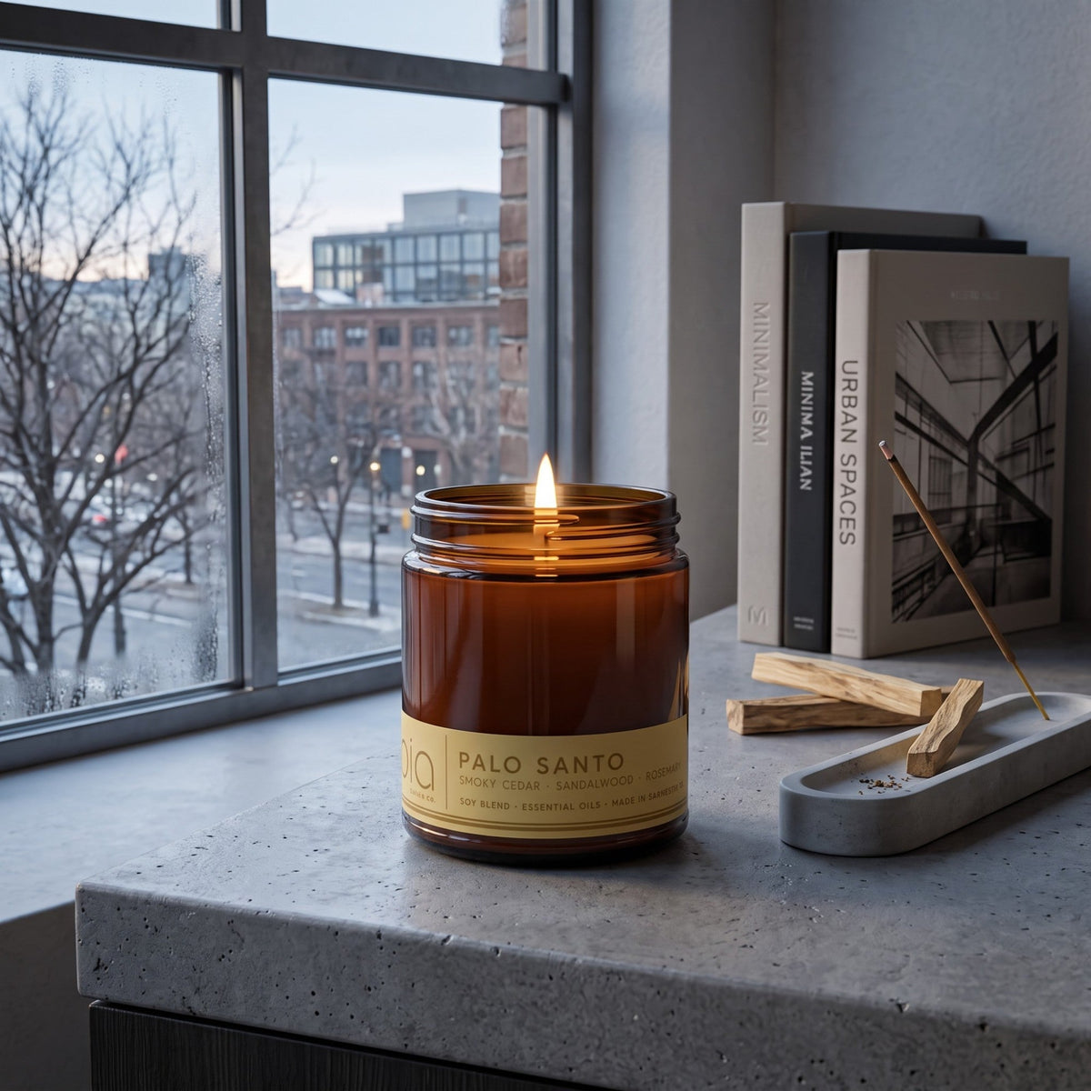 Amber soy candle jar with lit flame on a stone ledge