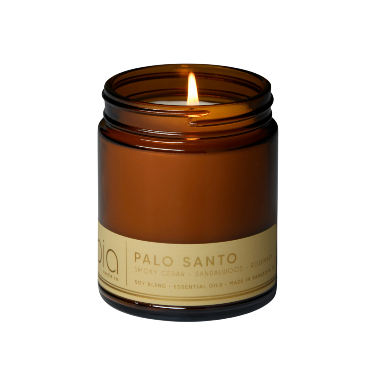 Amber glass soy candle jar with burning flame and gold “Palo Santo” label