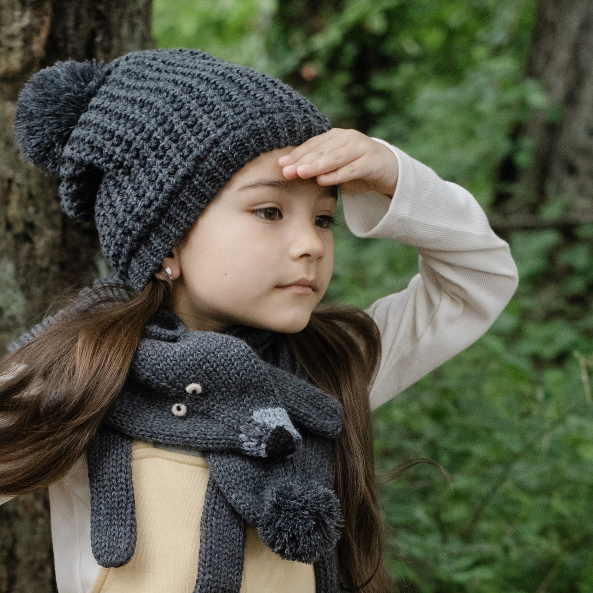 Dark gray textured knit beanie with pom-pom, shown from the side