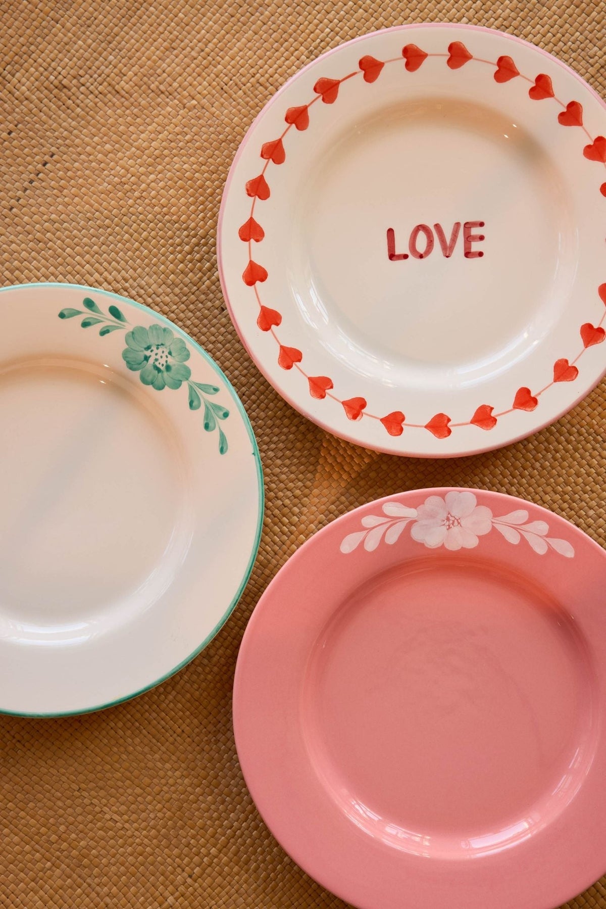Ceramic dinner plates, including LOVE plate with red border, plus pink and green-vine plates