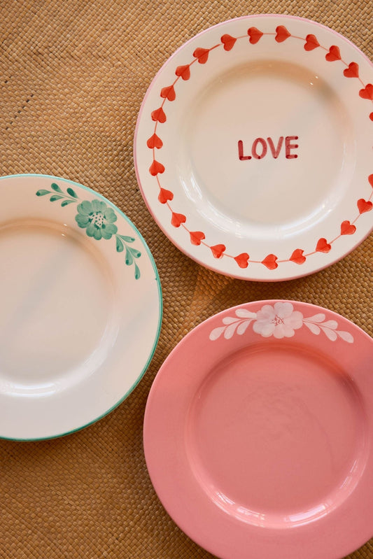 Ceramic dinner plates, including LOVE plate with red border, plus pink and green-vine plates