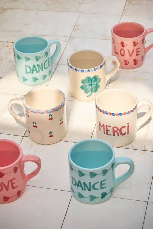 Ceramic mugs with colorful hand-painted icons and text, varied colors and handles
