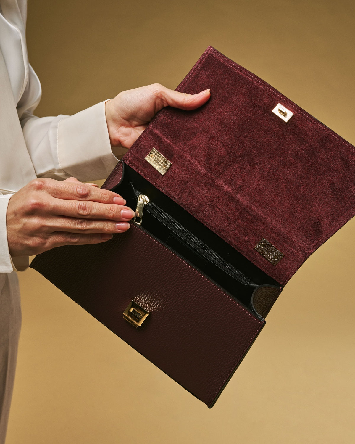 Eggplant leather crossbody bag open view with interior, gold clasps, and flap