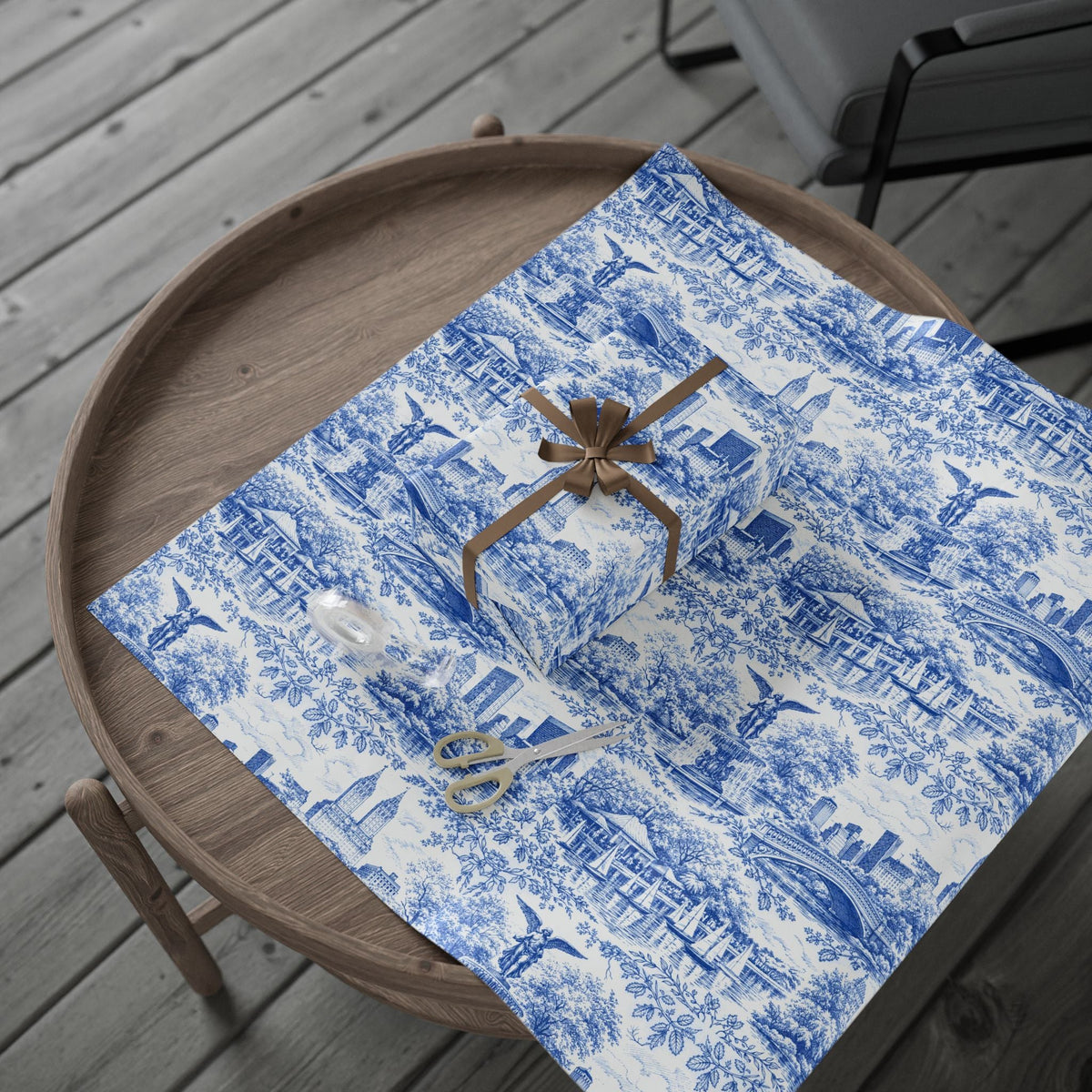 Blue-and-white toile wrapping paper gift with tan bow on wooden tray