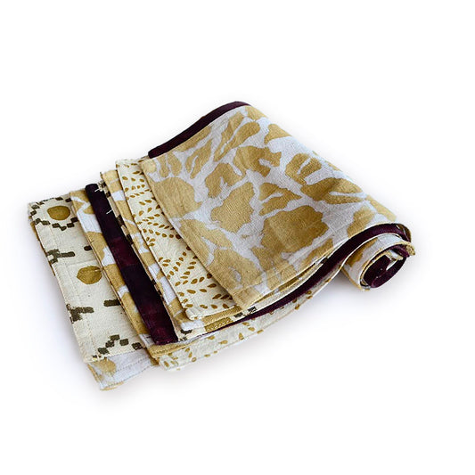 Folded cotton towel set with tan and cream animal-print patterns and maroon accents