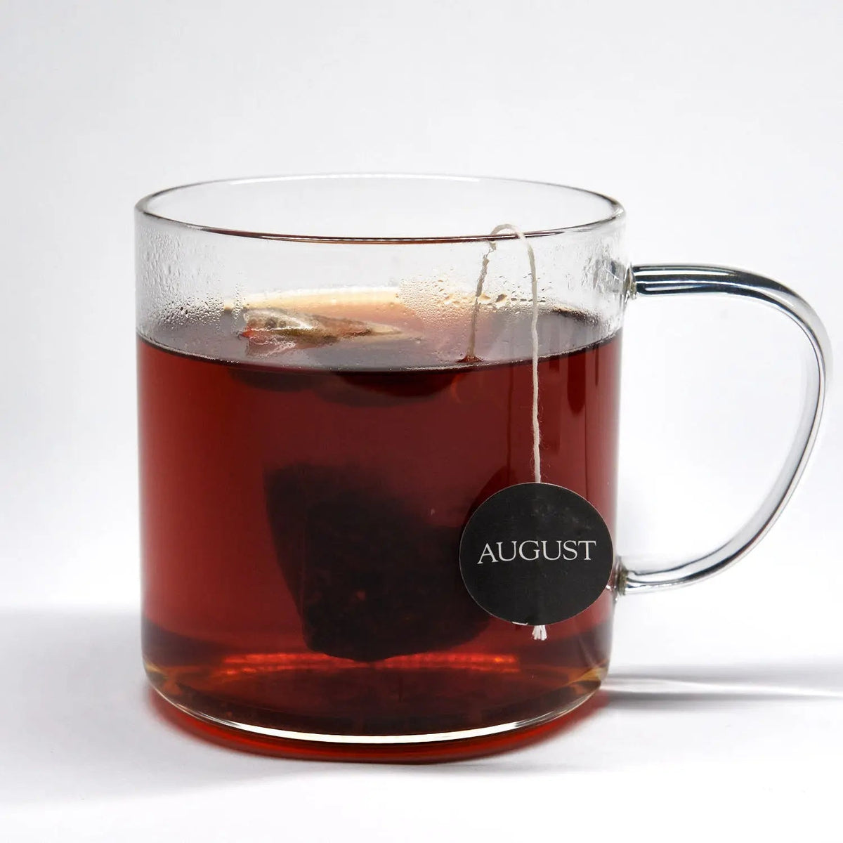 Dirty Chai tea brewed in a clear glass mug with a tea bag steeping inside.