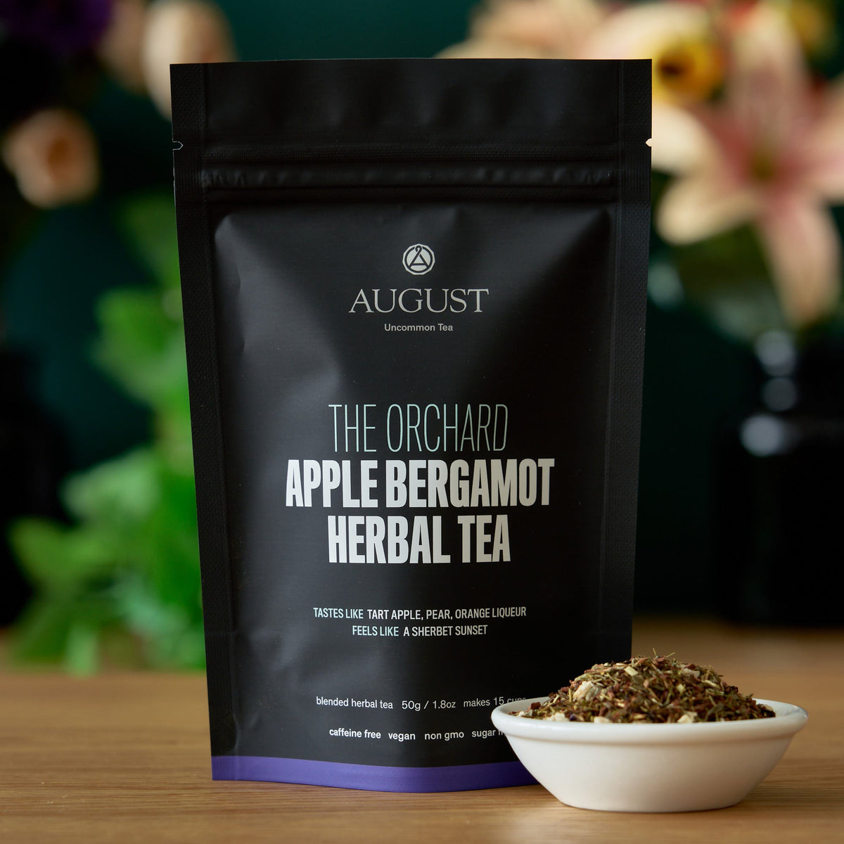 The Orchard apple bergamot herbal tea pouch with loose tea in a white bowl