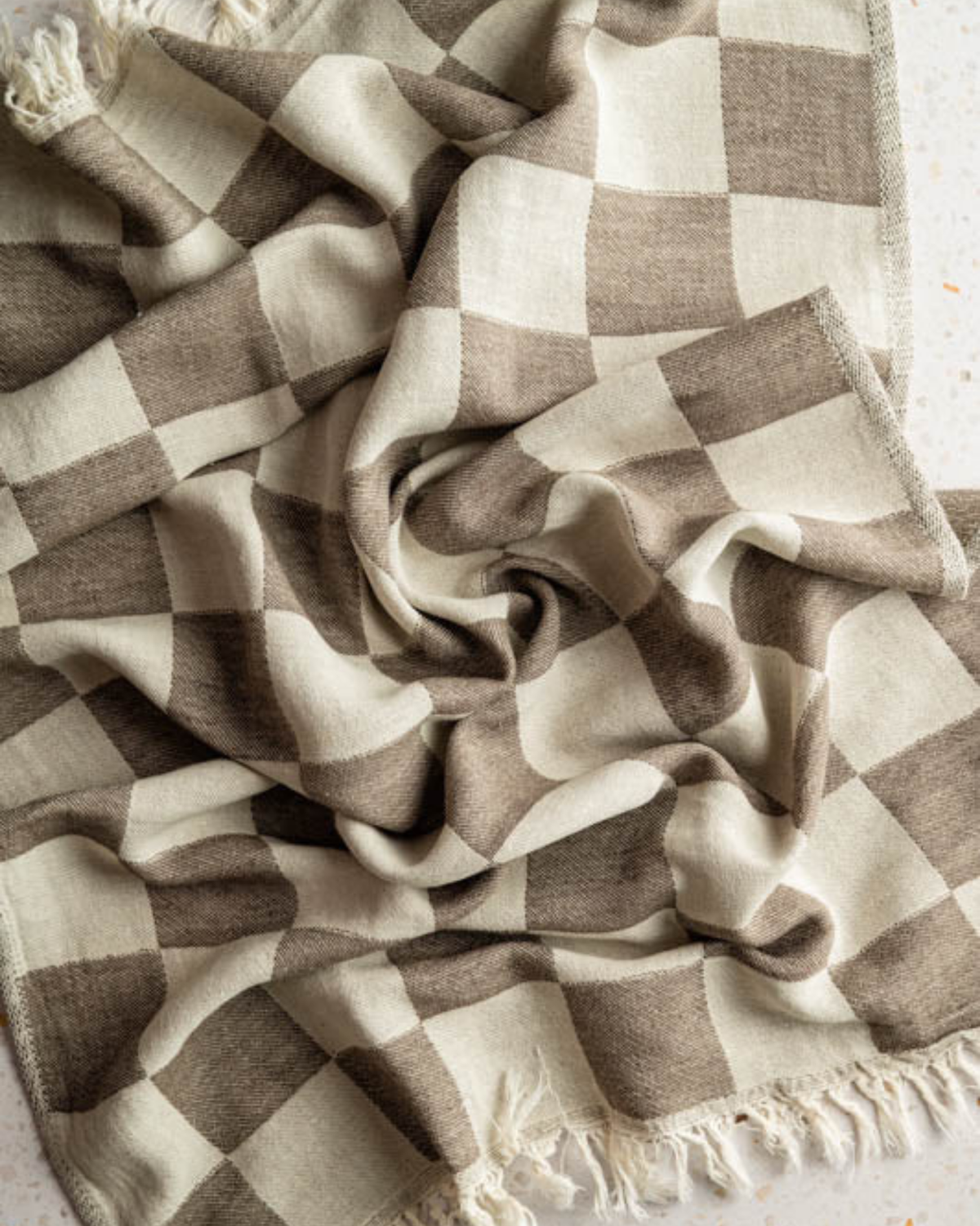 Beige and brown check tea towel fabric with green stripes and fringe