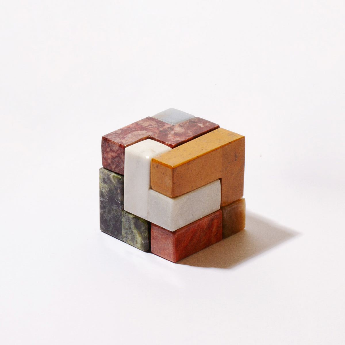 Gemstone cube puzzle with white and orange center, marbled green and black blocks.