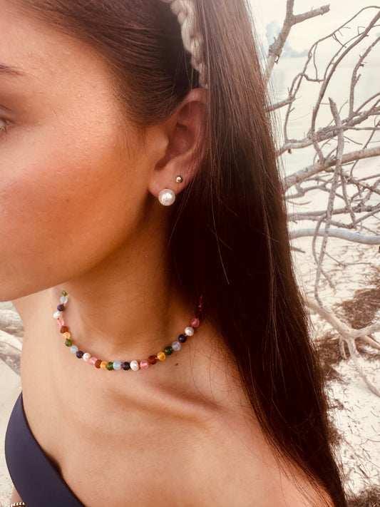 Multicolor beaded necklace worn close-up on the neck with small pearl earring