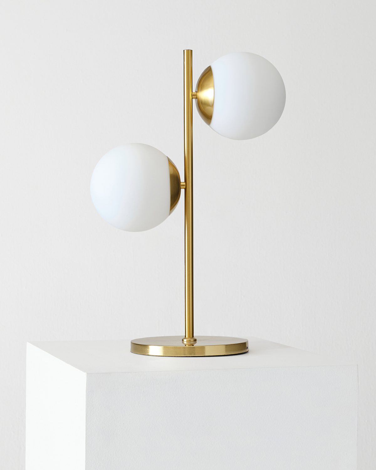 Two-light table lamp with two white globe shades, tall gold brass stem, round base