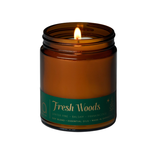 Amber soy blend candle in glass jar with lit wick and black lid
