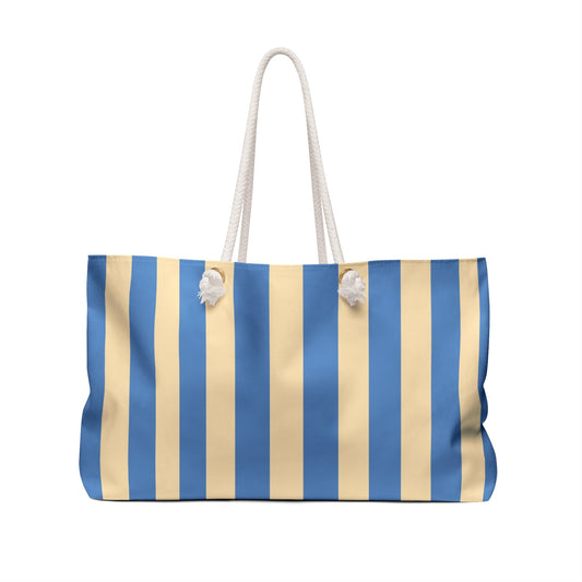 Blue and beige striped tote bag with rope handles and small tassel pom-pom accents