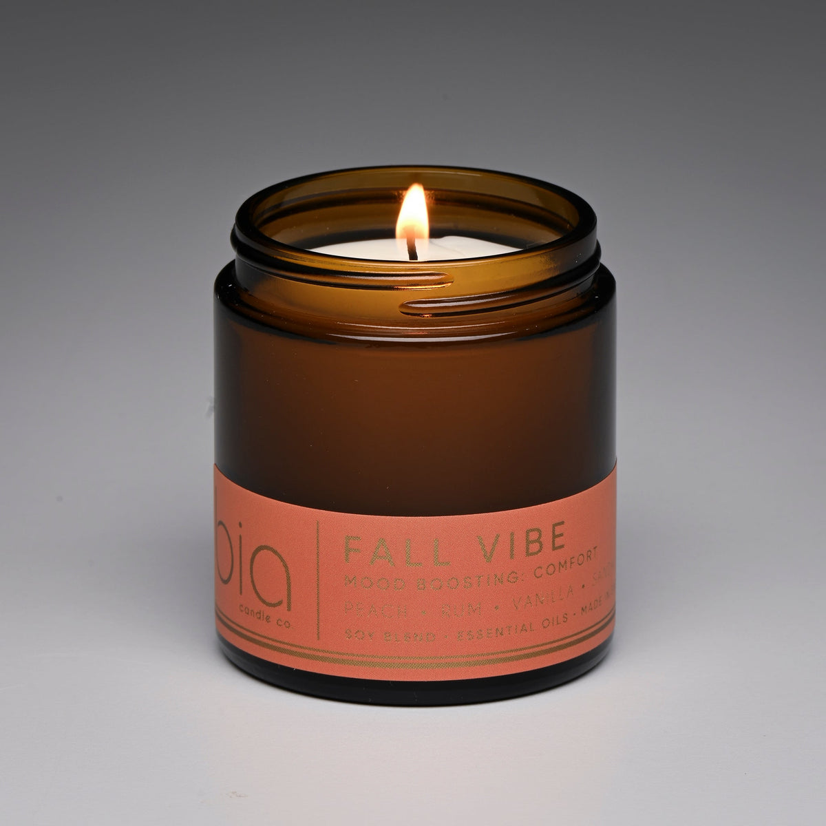 Amber glass jar candle with lit wick and printed label