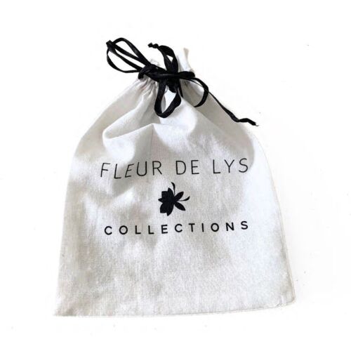 White fabric jewelry pouch with black bow and 'FLEUR DE LYS COLLECTIONS' print