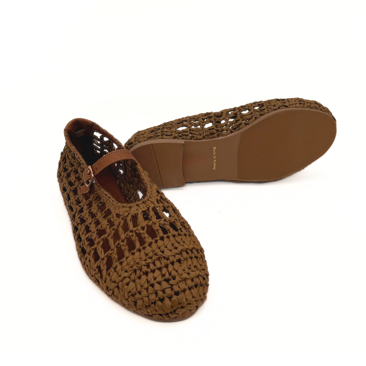 Brown raffia Mary Jane flats showing sole, with ankle strap and woven upper