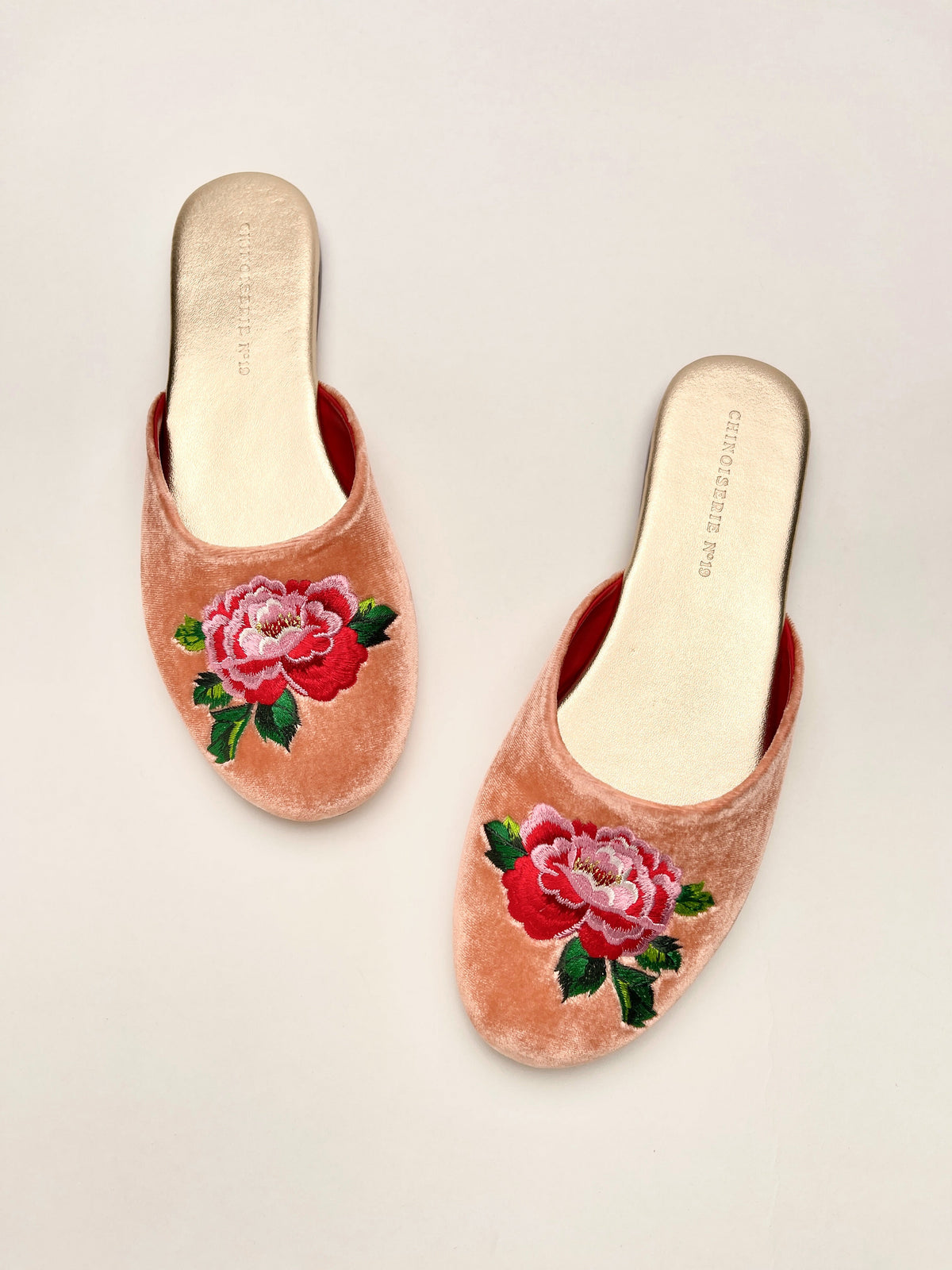Pair of peach velvet mules with red and pink peony embroidery on the front