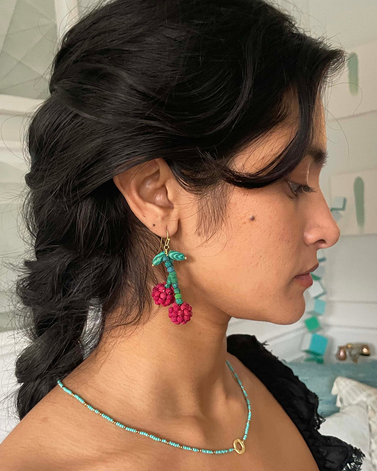 Teal and red beaded earrings with gold hooks, small leaf detail, and berry pom-poms.