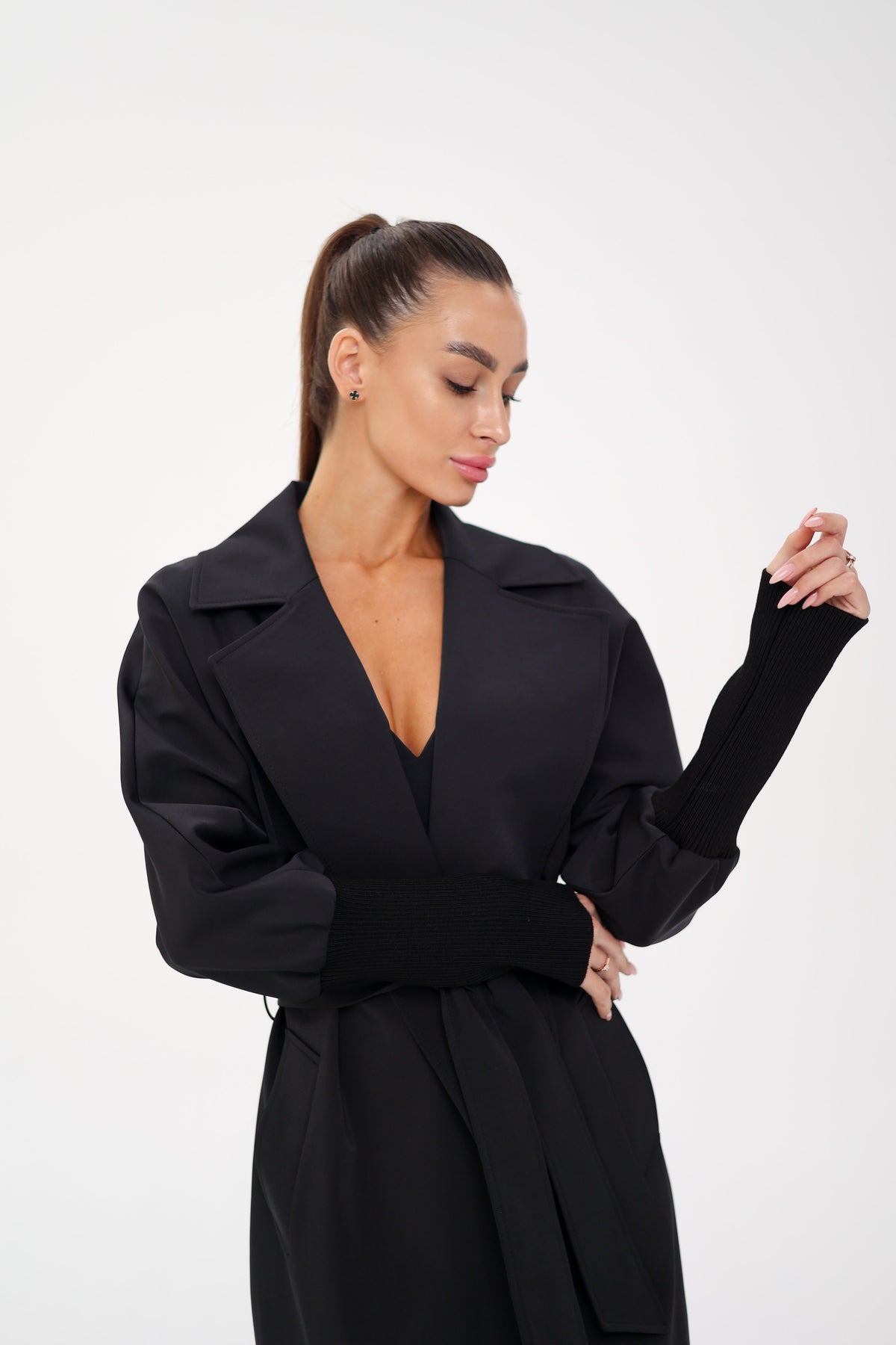Black trench coat detail showing wide lapels, gathered sleeves, and belt