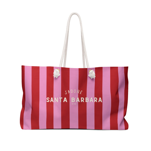 Striped pink and red weekender tote bag with white rope handles and charm details