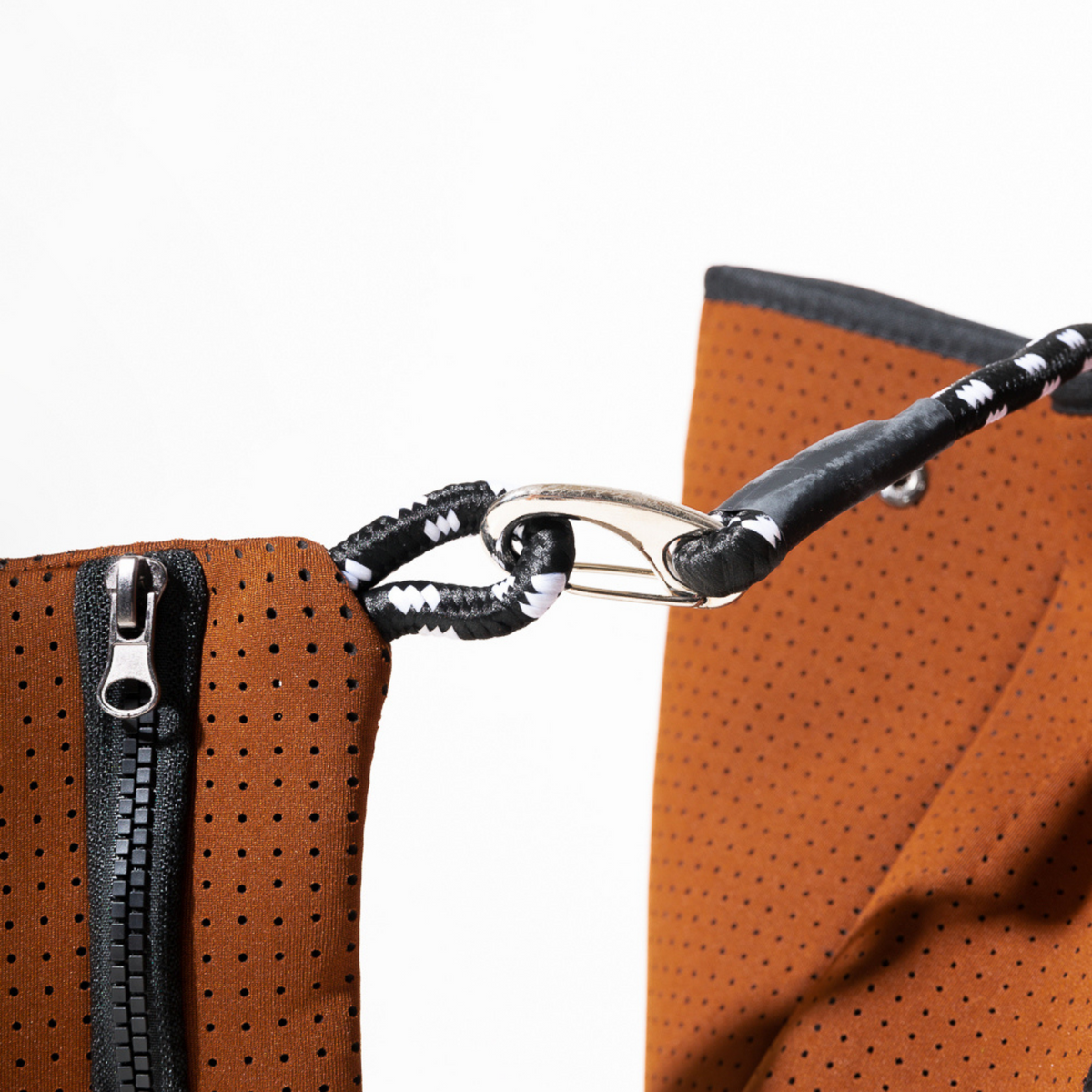 Rust-brown tote strap detail with black braided cord and metal clasp