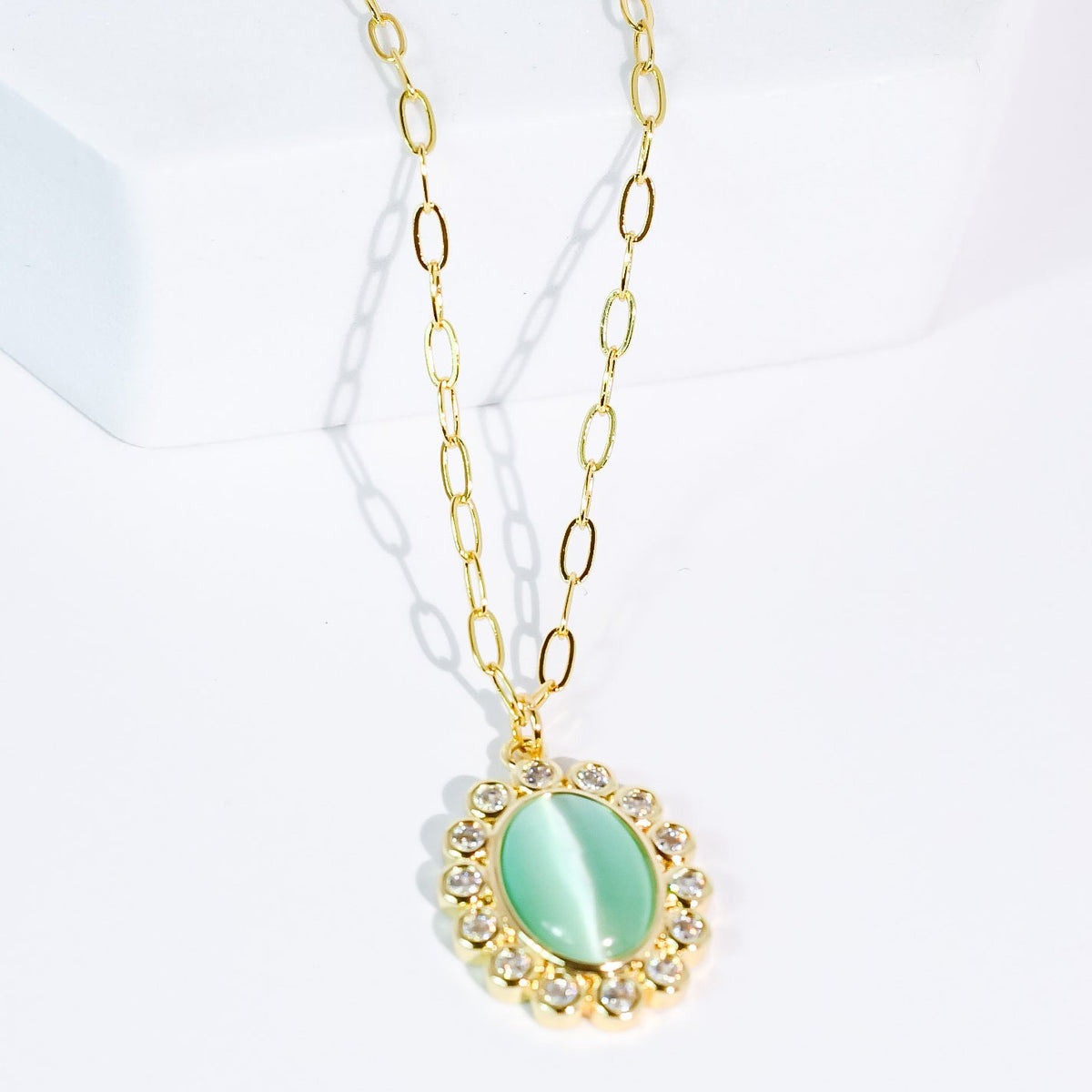 Gold-tone chain necklace featuring a mint oval pendant with sparkling crystal halo
