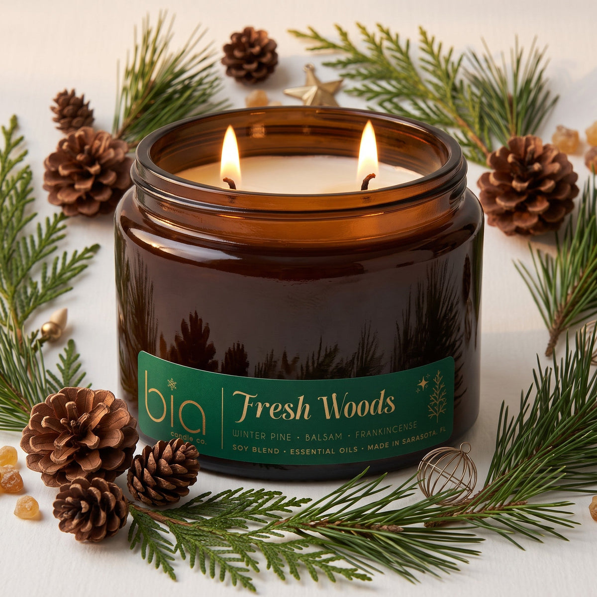Amber glass soy blend candle jar with green Fresh Woods label and two lit wicks