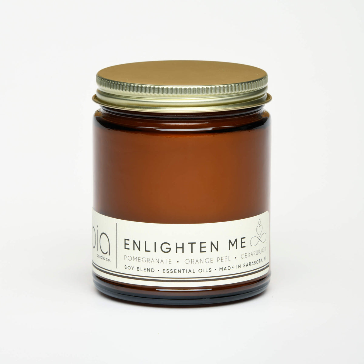 Amber glass candle jar with gold-green lid and white ENLIGHTEN ME label