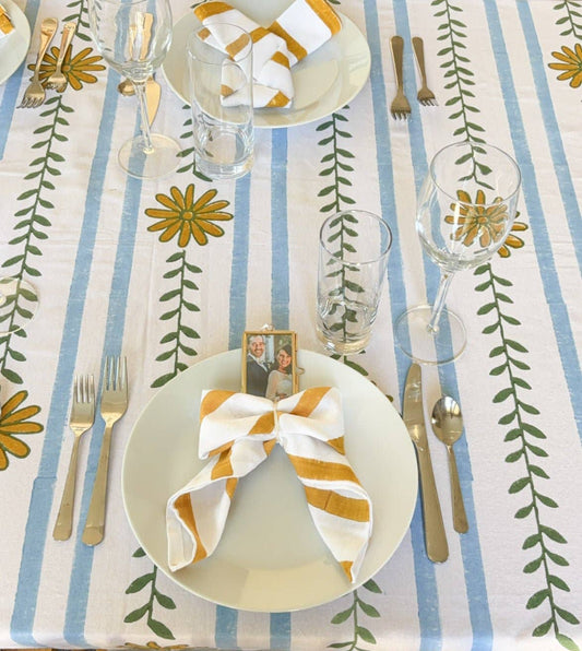 Table throw laid over table, featuring blue vertical stripes and green leaf motifs.