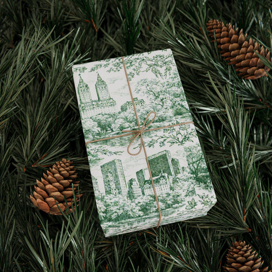 Green and white toile gift wrap with city buildings, trees, and brown ribbon tie