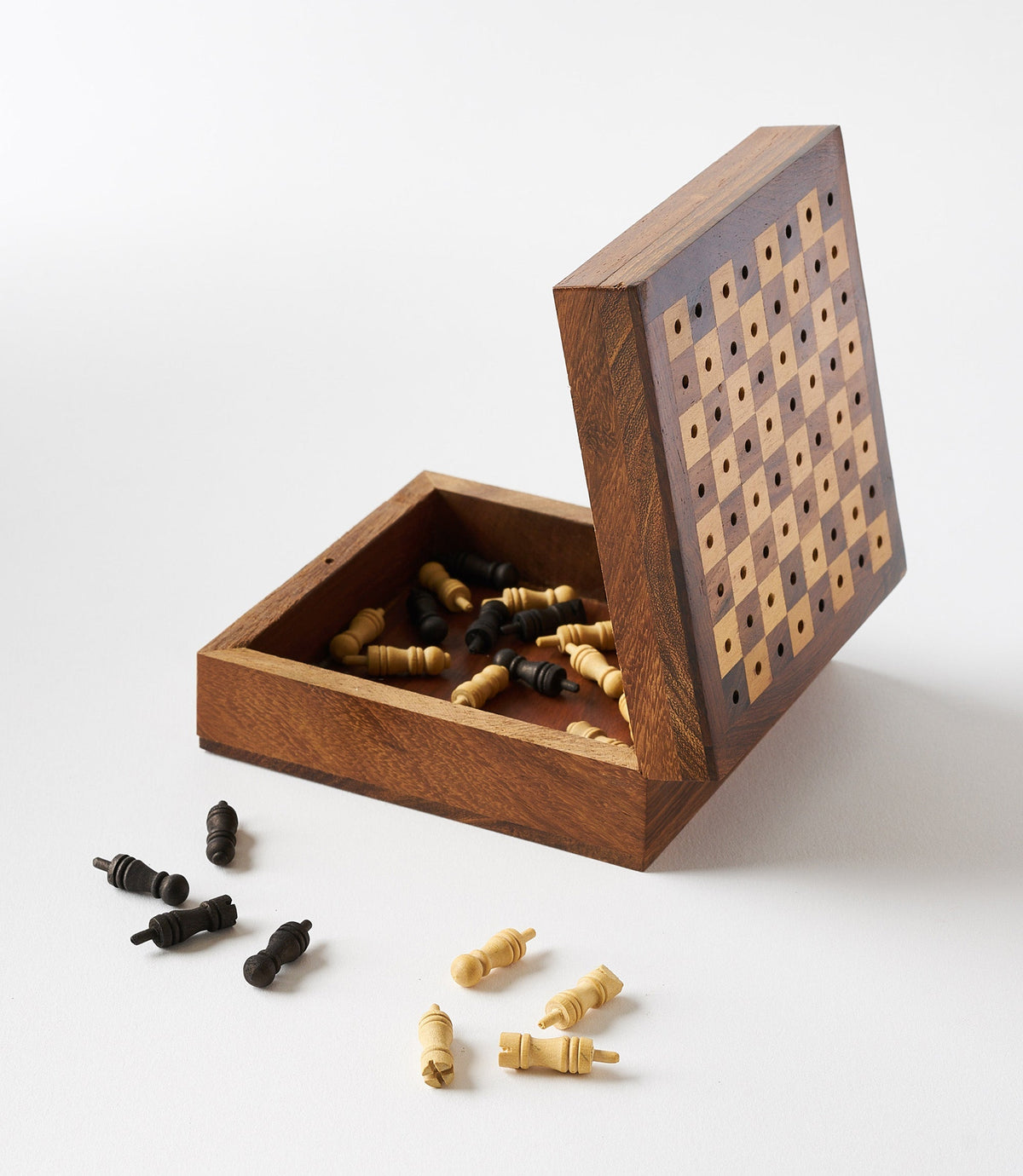 Open wooden travel chess game case with pegs inside and loose pieces nearby
