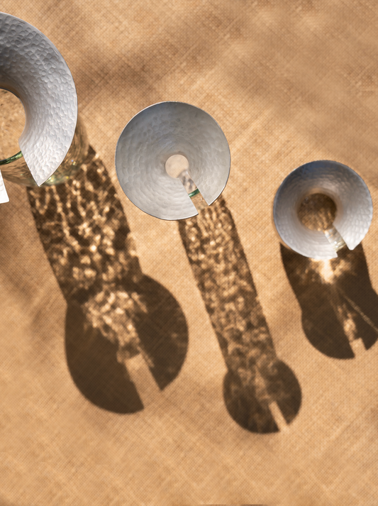 Three round silver lids on glass propagation vases on a burlap surface