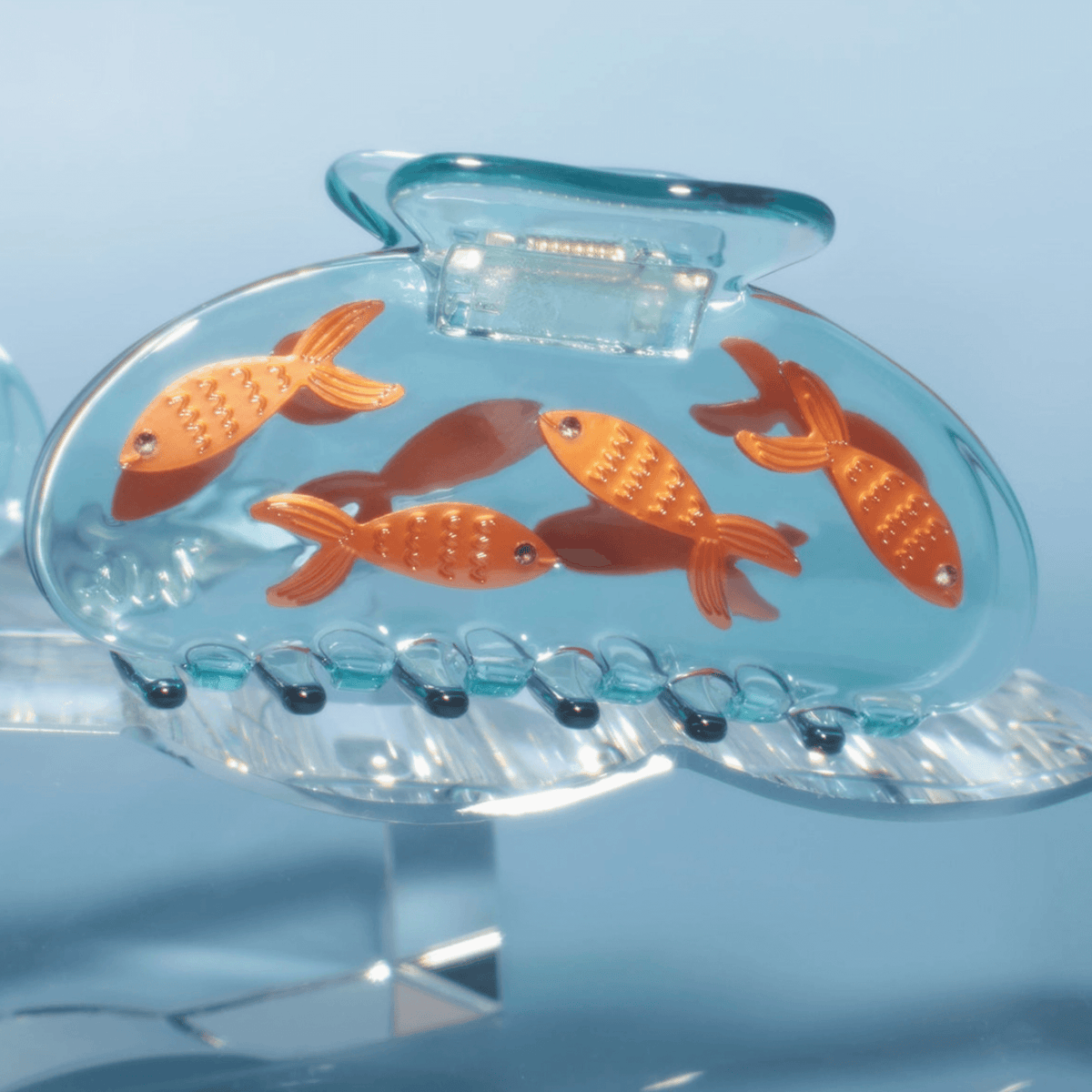 Clear blue fish hair claw featuring orange goldfish and a row of grip teeth