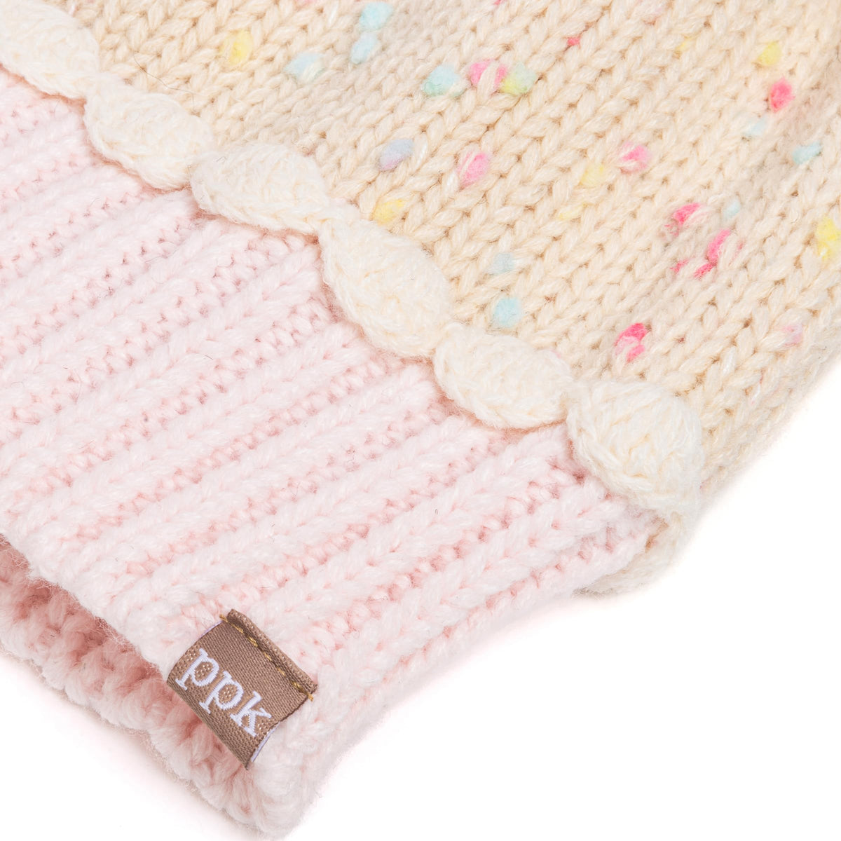 Close-up of cream scalloped trim, sprinkle-knit crown and pink ribbed cuff with logo tag