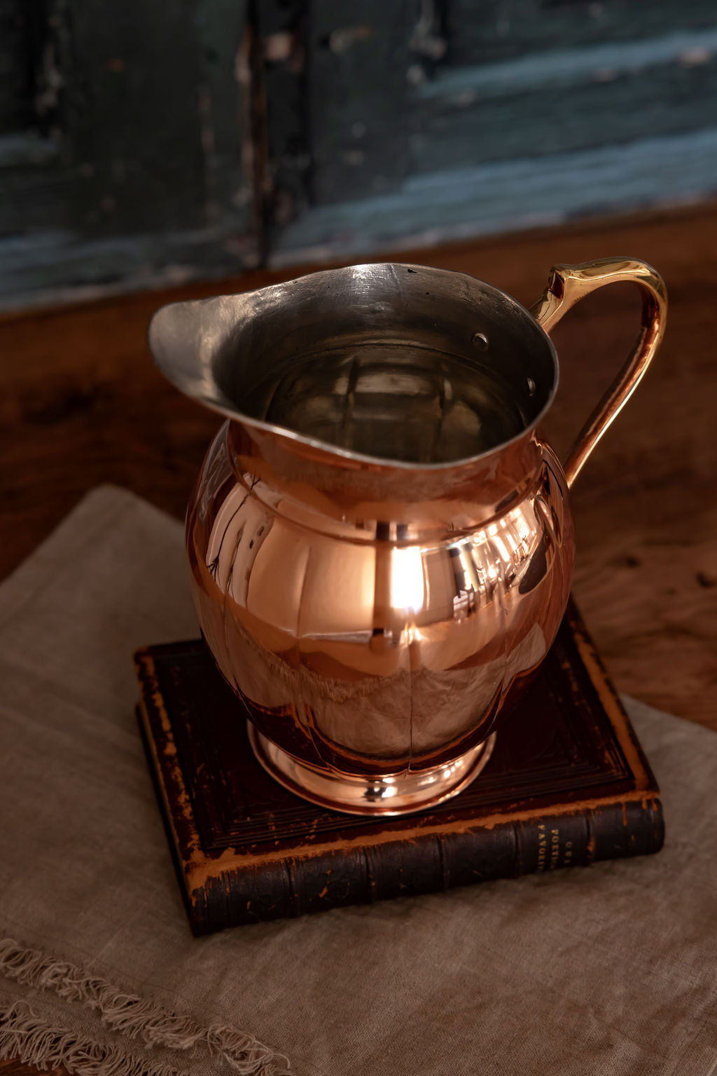 Copper metal pitcher with curved handle and flared spout, front close-up view.