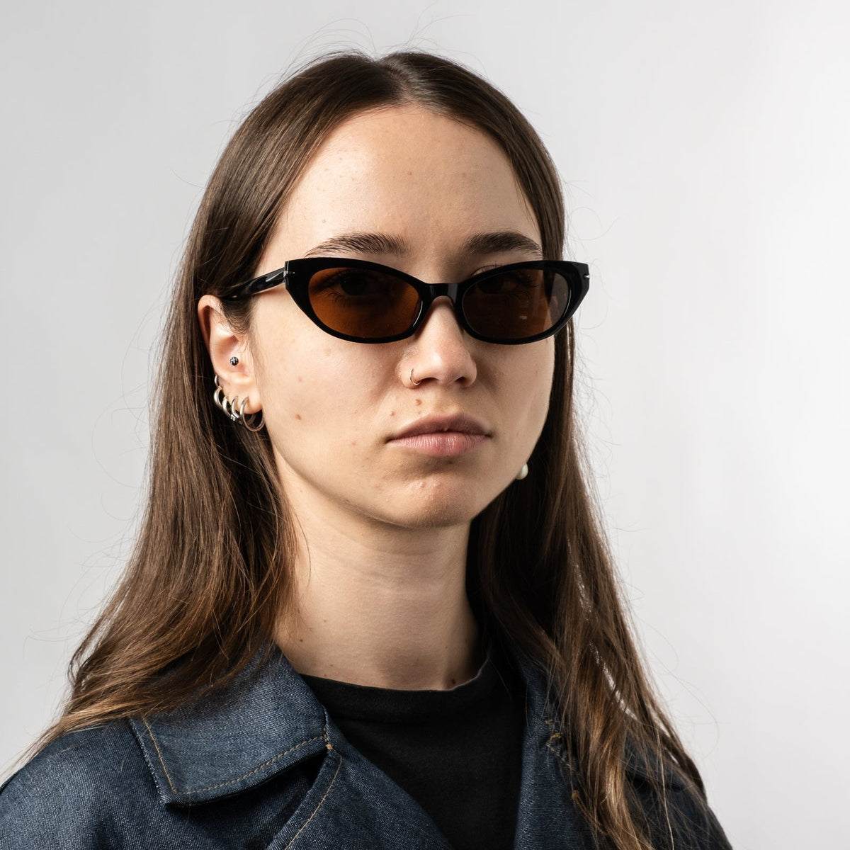 Person wearing black polarized sunglasses with bronze lenses and a denim jacket.
