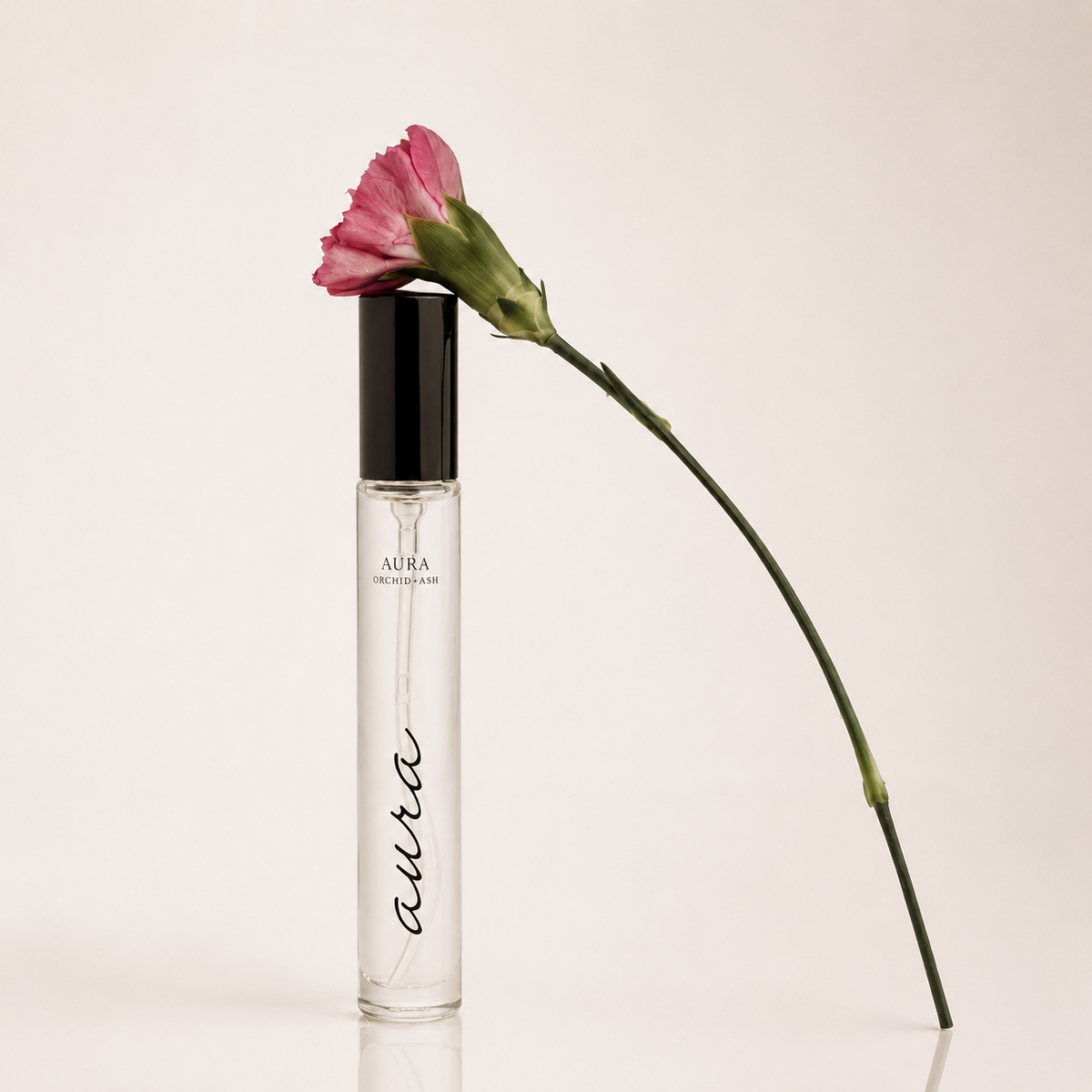 AURA perfume travel spray bottle with clear liquid and black cap, pink flower on stem